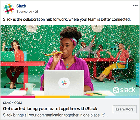 Dette er et skjermbilde av en Facebook-annonse for Slack. Annonseteksten sier "Slakk er samarbeidsnavet for arbeid, der teamet ditt er bedre koblet sammen." På annonsebildet sitter en svart kvinne ved et skrivebord med en grå bærbar PC. Håret er kort og holdt tilbake med et fargerikt pannebånd. Hun har på seg en fuschia-bluse og turkishalskjede, og hun blåser gjennom en gul støyemaker. I bakgrunnen sitter andre mennesker ved skrivebordet og har fargerike klær på. Kontoret er malt grønt, og konfetti faller ned fra taket. Talia Wolf anbefaler å bruke bilder som dette, som viser rå følelser, i annonsene dine.